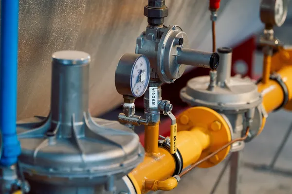 Fotografía de la diferencia de reguladores de gas de baja y alta presión, representada con un regulador conectado a tuberías amarillas.
